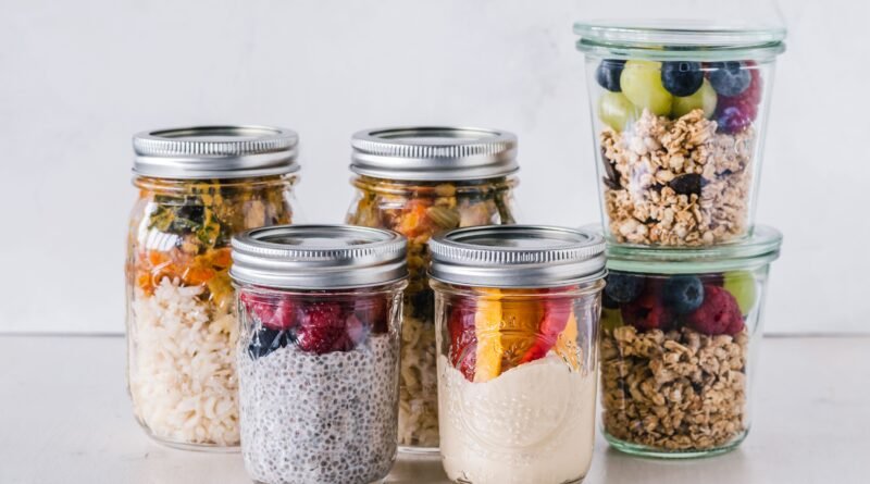 Athlete preparing healthy meal prep containers with lean protein, whole grains, vegetables, and fruit to support sports nutrition and athletic performance