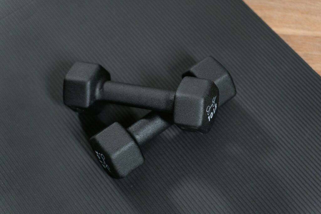 Flat lay of dumbbells, resistance bands, yoga mat, water bottle, and fitness journal.
