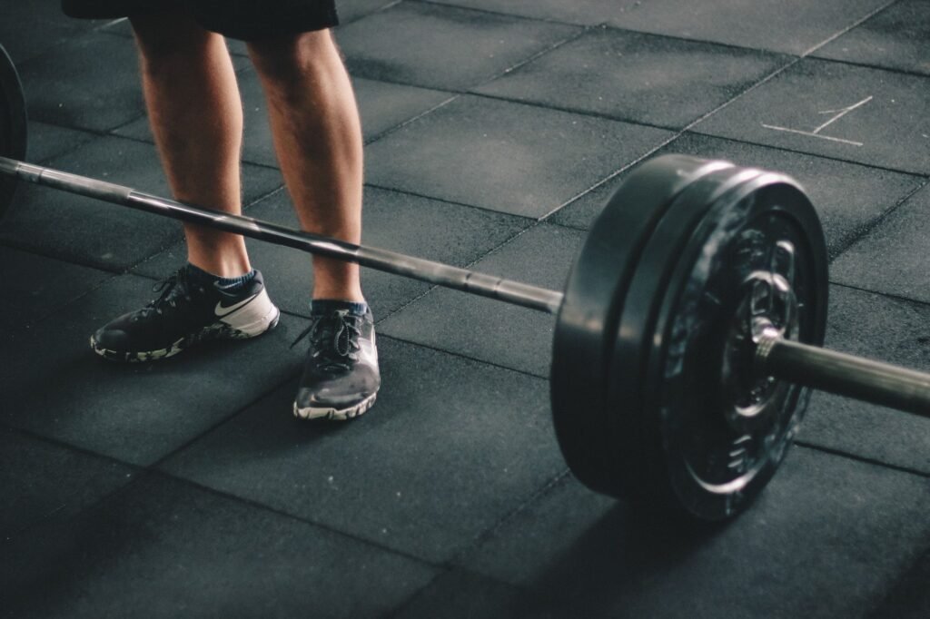 Fitness coach demonstrating mobility warm-up exercises before lifting weights.