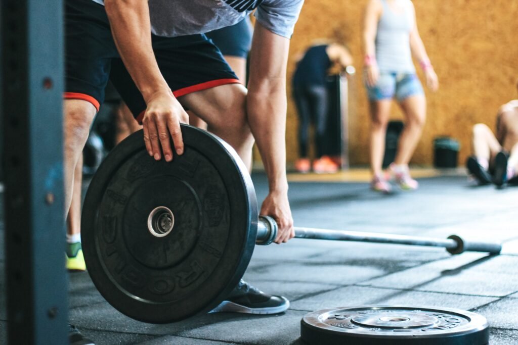 Older adult lifting light dumbbells with proper form in a modern fitness studio.