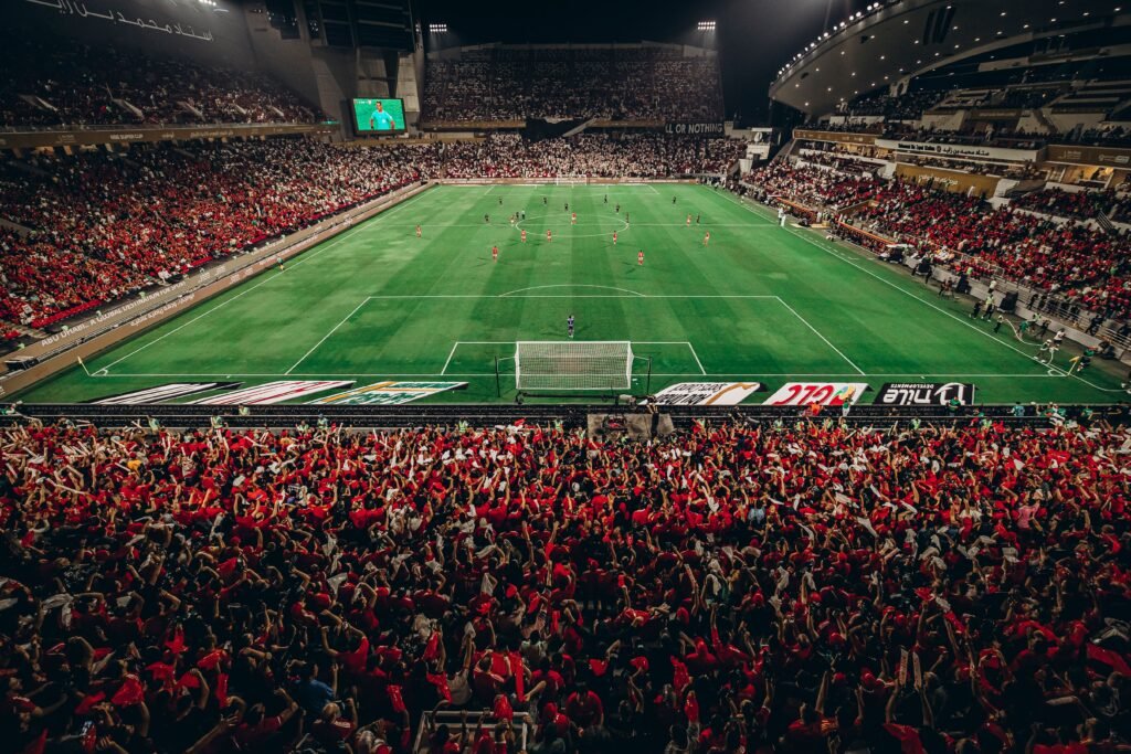 Passionate football supporters cheering in stadium stands during a Saudi Pro League game 